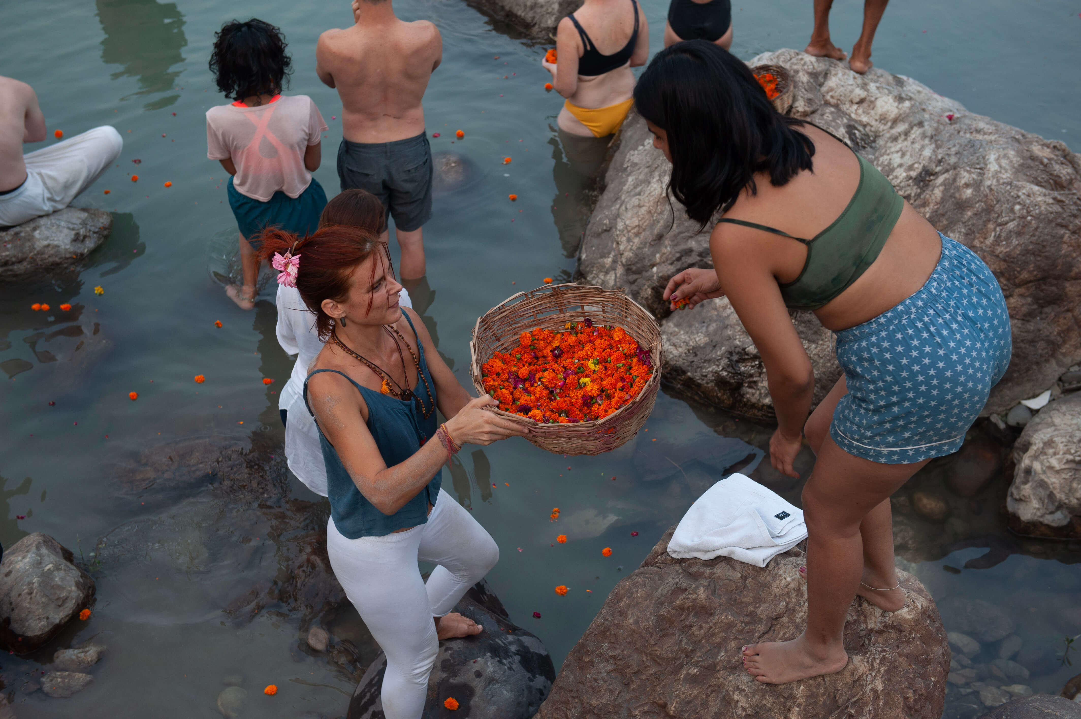 People standing in a river with bowl of flowers