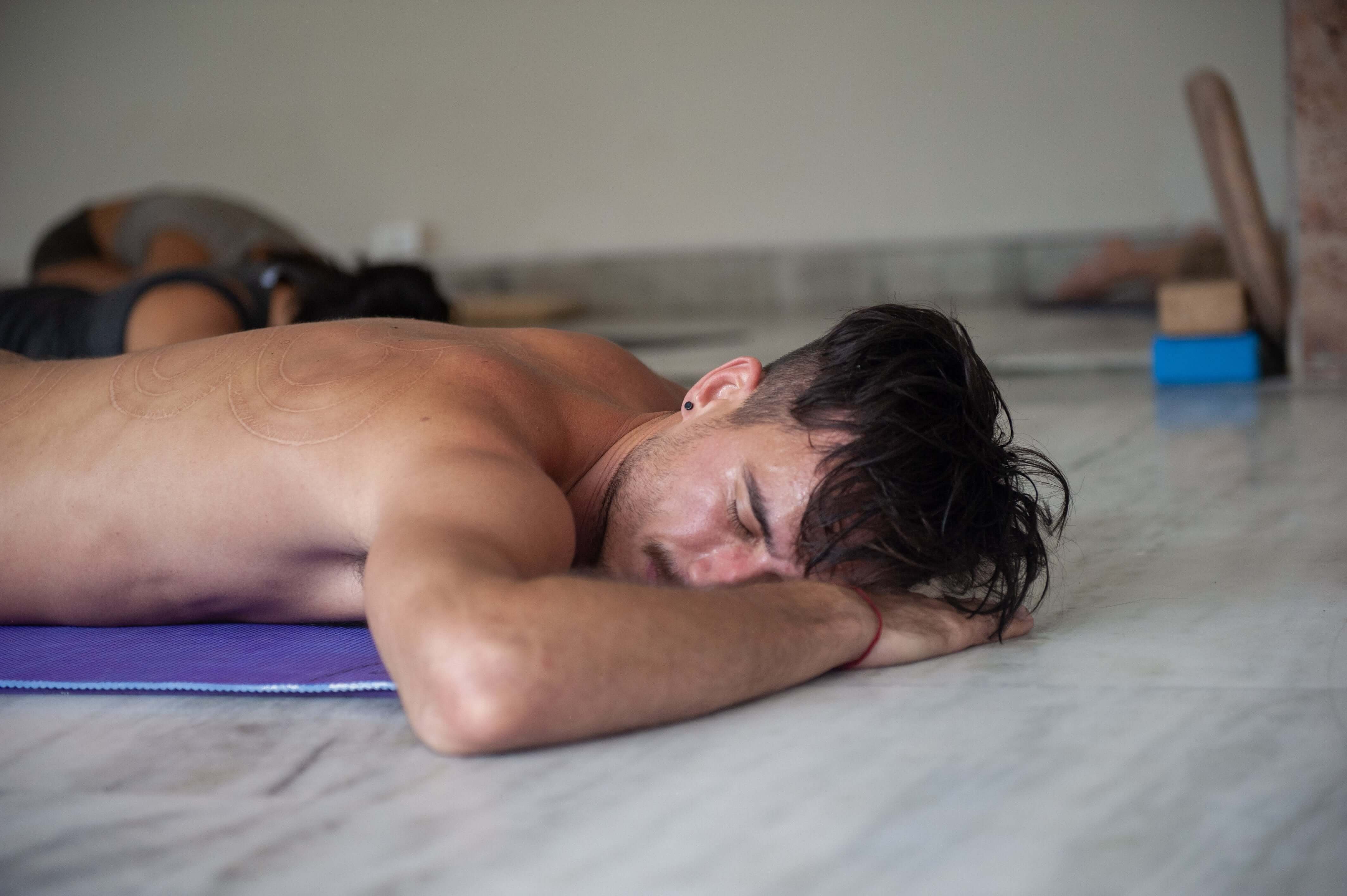 A man lying on the floor on a yoga mat