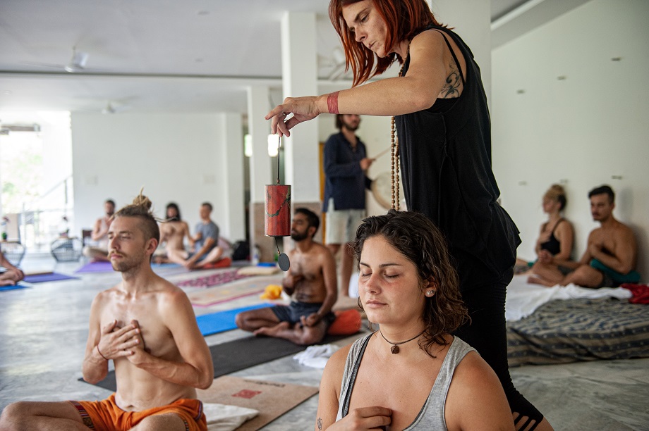 Yoga teacher performing sound healing exercise with an instrument in a yoga class